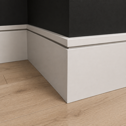 Close-up of a corner where a black wall meets a white baseboard on a wooden floor.