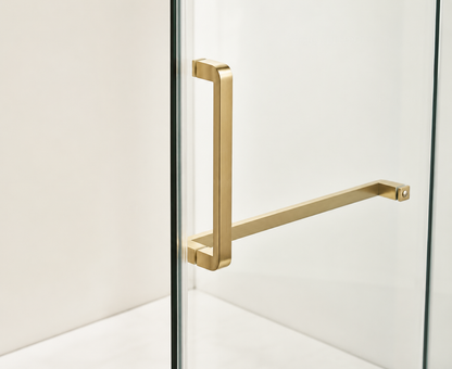 Gold towel bar mounted on a glass wall with a white background